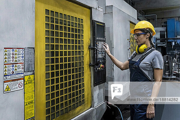 Engineer wearing hardhat operating CNC Machine in modern factory