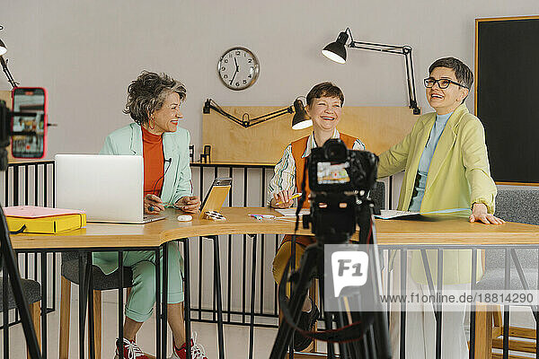 Drei Frauen sitzen im Studio und nehmen Videos mit der Kamera auf