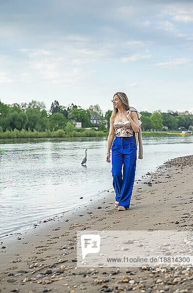 Lächelnde junge Frau  die am Flussufer spaziert