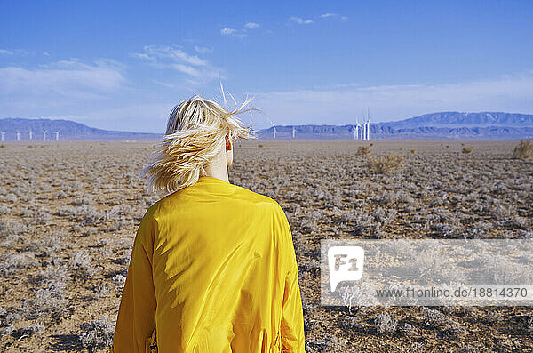 Blond woman with yellow raincoat standing in desert