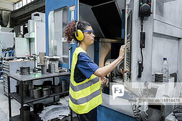 Maintenance engineer operating CNC machine in modern factory