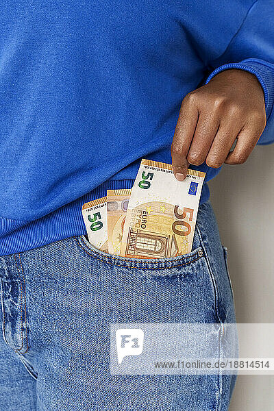Woman taking paper currency from jeans pocket