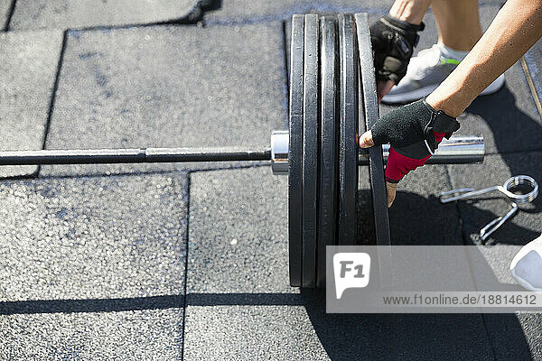 Woman preparing barbell weights at rooftop gym