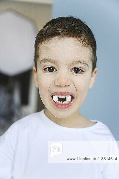 Junge hält Marshmallows zwischen den Zähnen