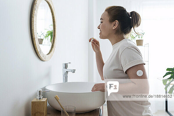 Woman with diabetes brushing teeth in bathroom at home