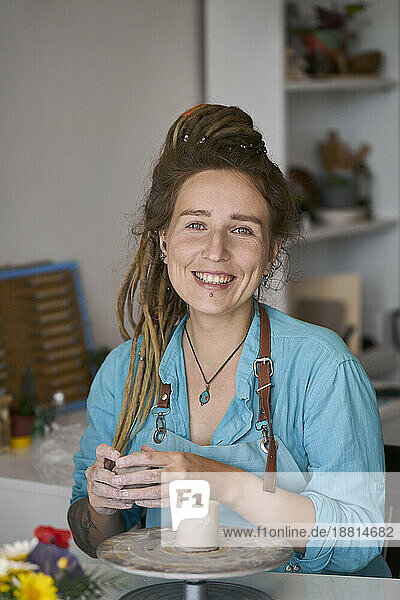 Smiling craftswoman making craft product at workshop