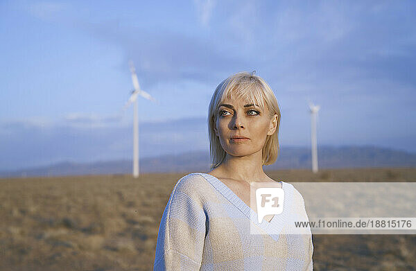 Blond woman standing near wind turbines in desert