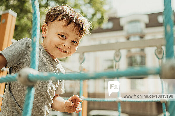Fröhlicher Junge  der sich an einem sonnigen Tag auf dem Spielplatz vergnügt