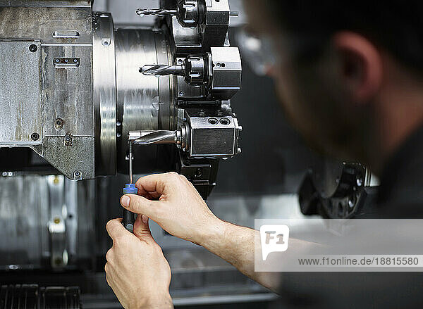 Technician repairing drill bit on metal machine in factory