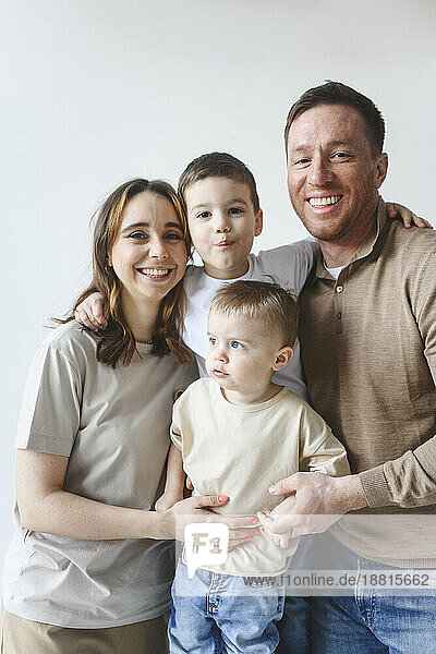 Happy father and mother with sons against white background