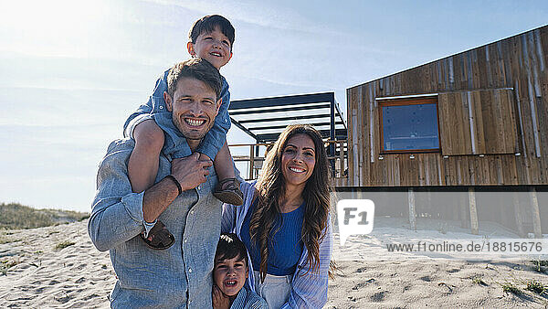 Happy family together standing in front of beach house