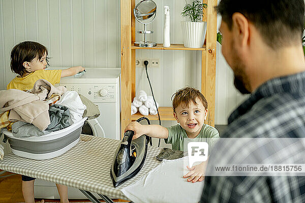 Vater und Sohn bügeln zu Hause Kleidung