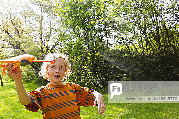Happy blond boy playing with airplane toy
