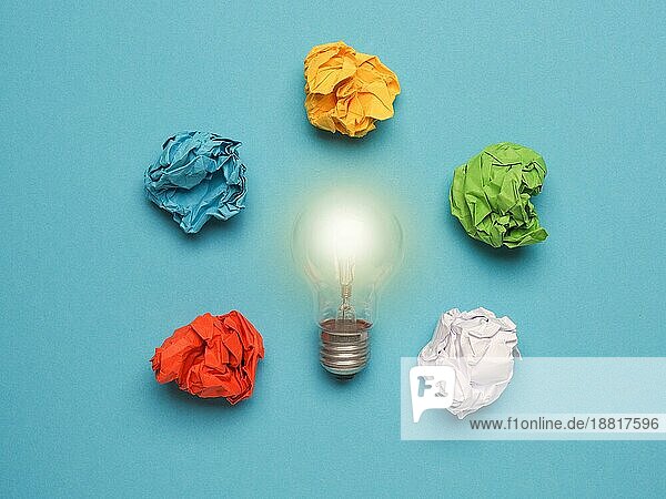 Glühbirne mit bunten zerknitterten Papierkugeln auf einem blaün Hintergrund  große Ideen Konzept  Kreativität  Denkweise  Macht