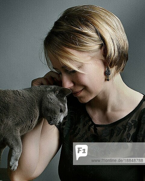 Portrait einer Frau mit ihrer Russisch Blau Rassekatze die ihre Zuneigung zeigt