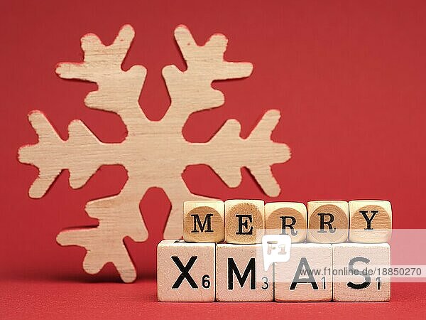 Holzblöcke mit den Worten Merry Christmas und einer Schneeflockenform auf rotem Hintergrund  Platz für Text