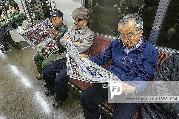 Tokio Japan. Ältere Fahrgäste in der U-Bahn  die Zeitung lesen