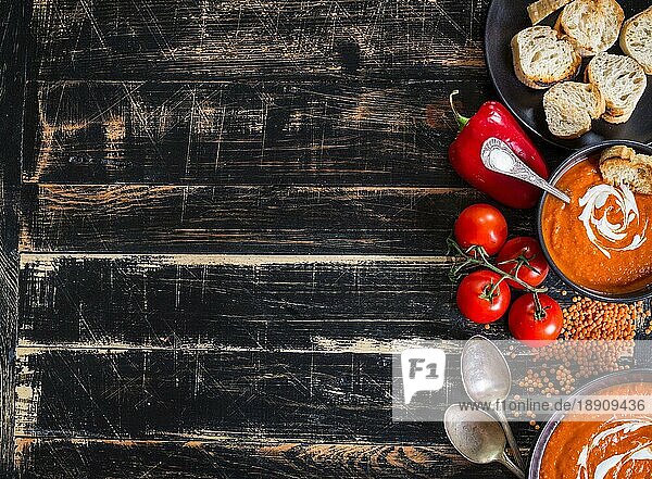 Leckere Kürbissuppe mit schwerer Sahne auf dunklen rustikalen Holztisch mit rotem Paprika  Toasts. AutumnHalloweenThanksgiving Tag Hintergrund. Ansicht von oben. Platz für Text