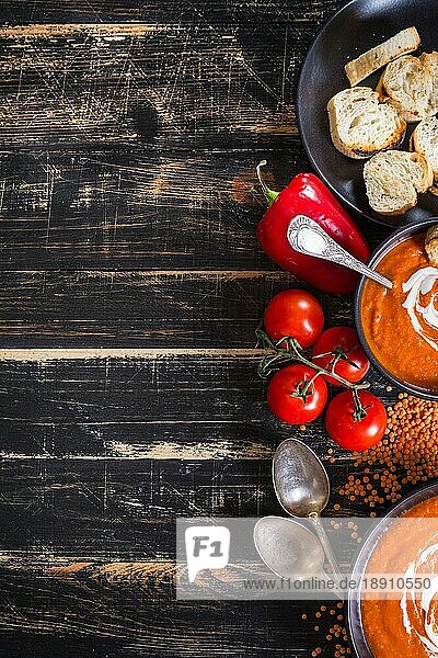 Leckere Kürbissuppe mit schwerer Sahne auf dunklen rustikalen Holztisch mit rotem Paprika  Toasts. Herbst/Halloween/Thanksgiving Tag Hintergrund. Ansicht von oben. Platz für Text