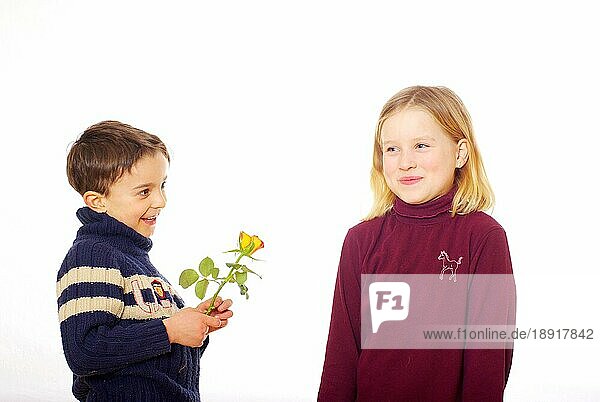 Junge überreicht Mädchen eine Rose  überreicht  überreichen  geben  schenken  schenkt  gibt  schüchtern