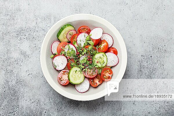 Nahaufnahme von frischen Sommer gesunden Salat in einer Schüssel aus Tomaten  Gurken  Radieschen und Kräutern  gut für Diät  Detox oder gesunde saubere Ernährung  grau rustikalen Stein Hintergrund  Ansicht von oben
