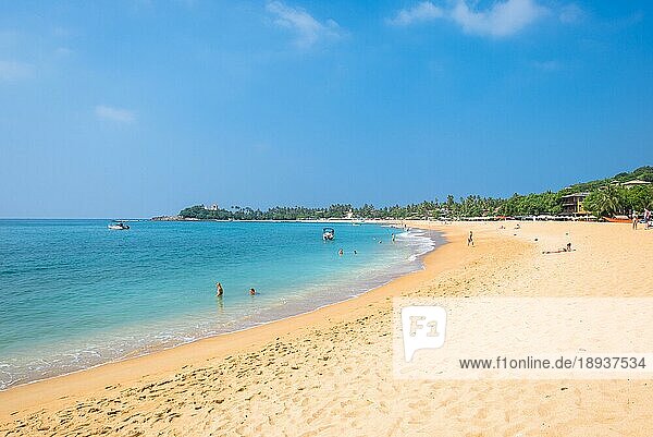 Am Strand von Unawatuna  einem der wichtigsten Touristenorte im Südwesten Sri Lankas  in der Nähe von Galle. Touristen nehmen ein Sonnenbad  entspannen sich und treiben Wassersport