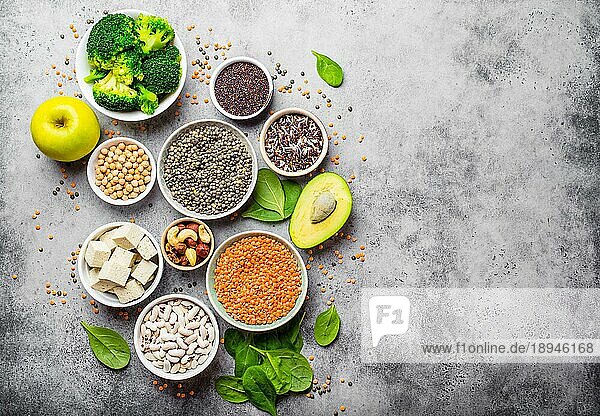 Vielfalt an nährstoffreichen Lebensmitteln für Veganer mit Kopierfläche: Bohnen  Linsen  Quinoa  Tofu  Gemüse  Nüsse  Kichererbsen  Reis  Avocado  Obst  Steinhintergrund  Draufsicht. Gesunde vegetarische Ernährung