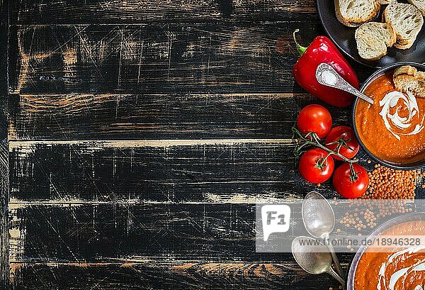 Leckere Kürbissuppe mit schwerer Sahne auf dunklen rustikalen Holztisch mit rotem Paprika  Toasts. AutumnHalloweenThanksgiving Tag Hintergrund. Ansicht von oben. Platz für Text