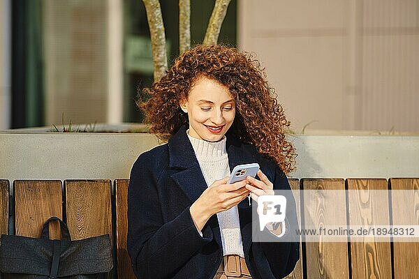 Lächelnde süße Frau mit Smartphone im Freien