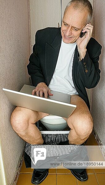 Ein arbeitswütiger erwachsener Geschäftsmann benutzt den Computer  den Laptop und das Mobiltelefon  auch Smartphone genannt  während er auf der Schüssel in der Toilette sitzt