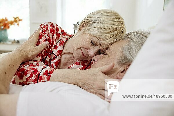 Älteres Paar  das zusammen im Bett im Schlafzimmer liegt und sich zärtlich umarmt  Köln  Nordrhein-Westfalen  Deutschland  Europa