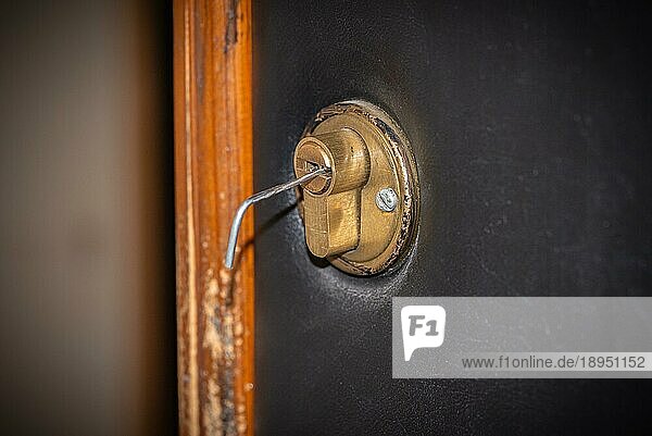 Lock Picking  ein Spannschlüssel wird in das Schloss einer Sicherheitstür eingeführt