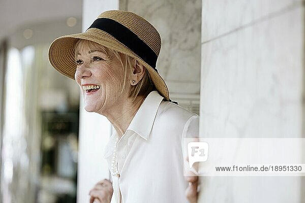 Fröhliche  lächelnde  ältere  sommerlich gekleidete Frau mit Strohhut und Perlenkette  Porträt  Köln  Nordrhein-Westfalen  Deutschland  Europa