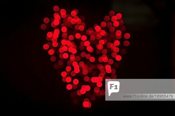 Herz aus glänzenden Bokeh Lichter in roter Farbe auf einem dunklen Hintergrund am Valentinstag gemacht