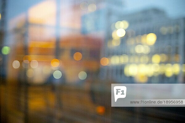 Tagtraum fotografiert aus dem Fenster eines Zuges. Unscharfes Bild mit Lichtern einer Stadt und der Spiegelung eines Zugabteils