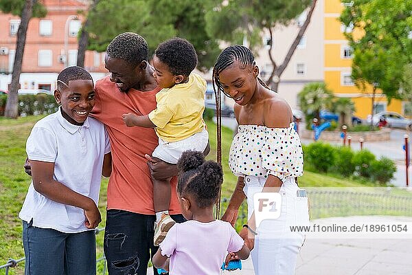 Afrikanische Familie schwarzer Ethnizität  die Spaß mit glücklichen Kindern auf dem Spielplatz hat  die sich nach der Schule gegenseitig begrüßen
