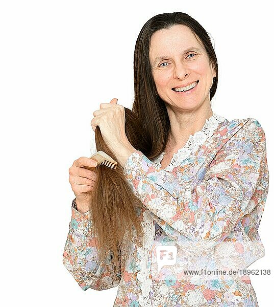 Erwachsene Frau kämmt langes braunes Haar mit einem Holzkamm  vor weißem Hintergrund