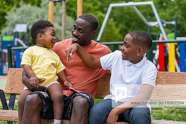 Afrikanischer  schwarzer  ethnischer Vater hat Spaß mit seinen Kindern auf dem Spielplatz des Stadtparks