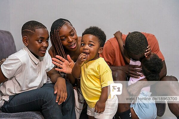 Afrikanische  schwarze  ethnische Familie mit Kindern auf dem Sofa in ihrer Wohnung