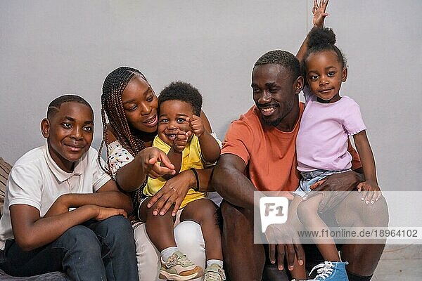 Afrikanische  schwarze  ethnische Familie mit Kindern auf dem Sofa in ihrer Wohnung