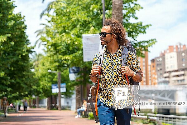 Afrohaar Mann auf Rucksacktour im Sommerurlaub  Lebensstil außerhalb eines Touristen auf Reisen