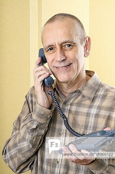 Heller Mann lächelt beim Telefonieren