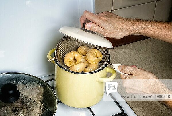 Zubereitung köstlicher traditioneller gedämpfter Pelmeni in einem gelben Topf