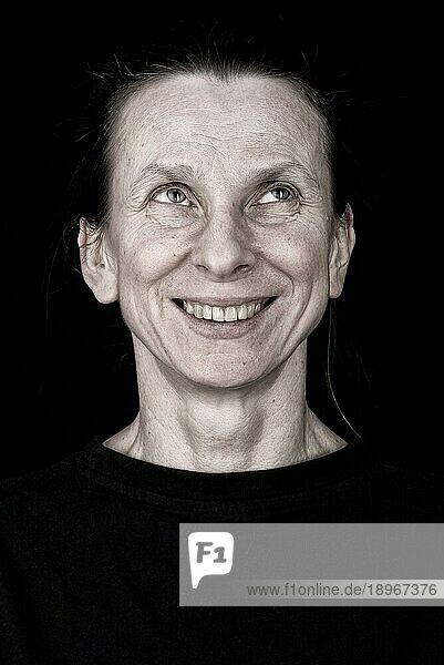 Porträt einer attraktiven erwachsenen Frau  die nach oben schaut und lächelt