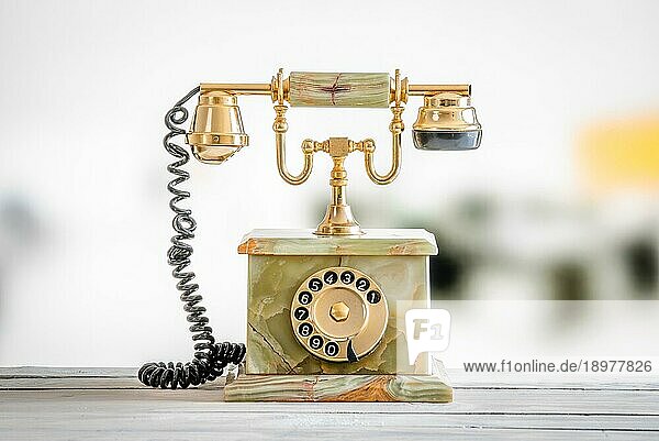 Antikes Telefon in Gold und Marmor auf einem Holztisch