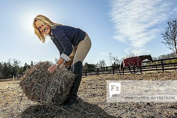 Eine schöne blonde Pferdetrainerin kümmert sich um ihre Pferde auf einem Bauernhof