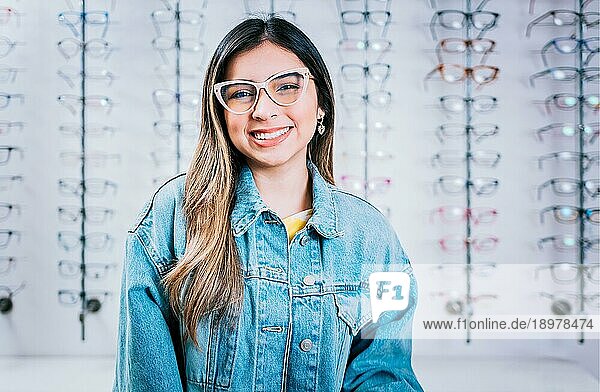Lächelndes glückliches Mädchen mit Brille mit Brillengeschäft Hintergrund  Porträt eines glücklichen Mädchens mit Brille in einem Brillengeschäft