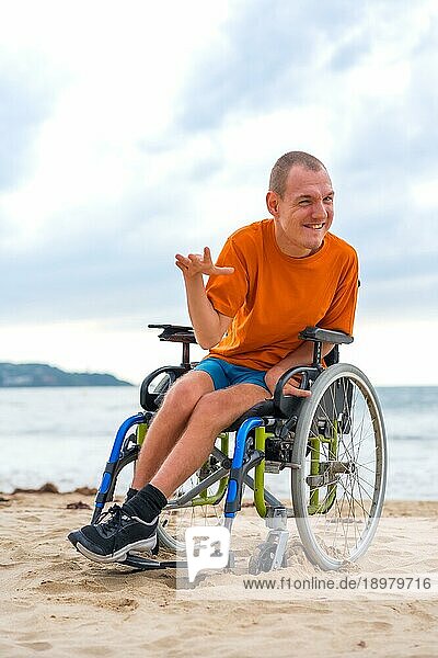 Eine behinderte Person im Rollstuhl am Strand im Sommer lachend