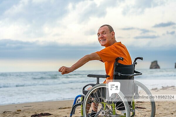 Eine behinderte Person auf dem Rücken in einem Rollstuhl am Strand im Sommer am Meer