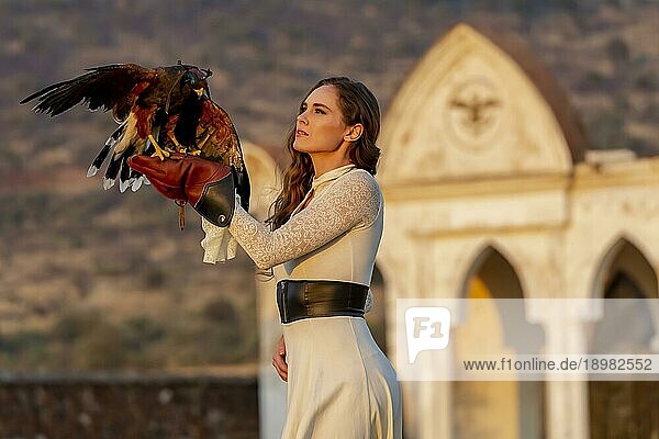 Eine wunderschöne Hispanic Brunette Modell posiert im Freien mit einem Falken im Freien auf einer Hazienda